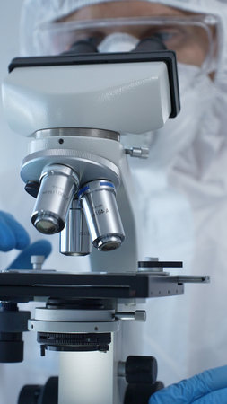 Close up of medical virologist in a hazmat suit, mask, and gloves, diligently working at a...