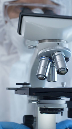 Close up of medical virologist in a hazmat suit, mask, and gloves, diligently working at a...