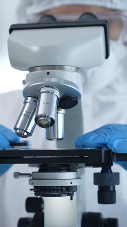 Medical virologist in a hazmat suit, mask, and gloves, diligently working at a microscope in a...