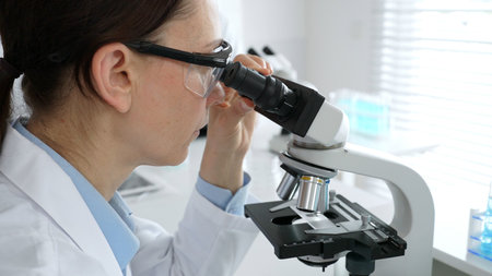 Female scientist examining microscope slide, analyzing research data in sterile laboratory...