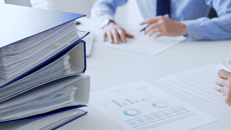 Group of accountants are analyzing financial reports and making notes while sitting at a white...