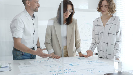 Professional team reviewing financial data, sharing success, collaborating around workplace...
