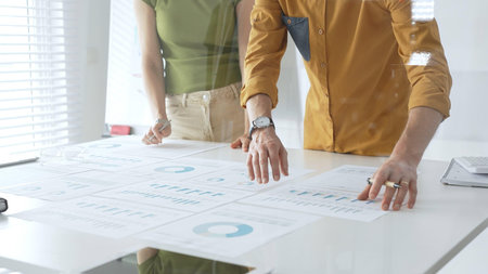 Business team members are reviewing financial data, analyzing charts and graphs, during a productive...