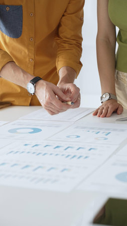 Business professionals analyzing financial reports, pointing at data points on charts and graphs...