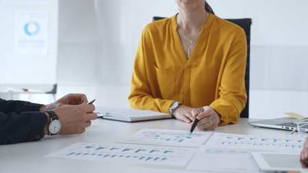 Business people team collaborating and analyzing financial data while taking notes during a corporate meeting in a modern officeの写真素材