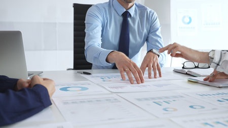 Business professionals study financial charts and graphs during corporate meetings, focusing on data...