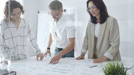 Professional team analyzing financial data, colleagues looking at charts in modern workplace....