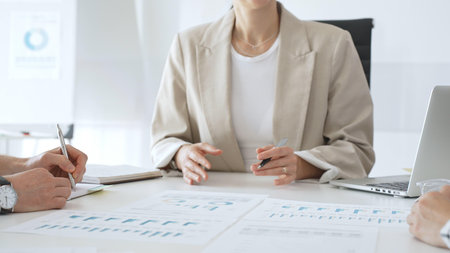 Professional team reviewing financial charts, collaborating on data analysis and strategic planning in modern corporate workspace, emphasizing teamwork and productivityの写真素材