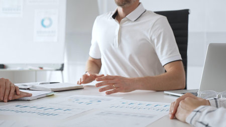 Professional team reviewing financial charts, collaborating intently around conference table in...