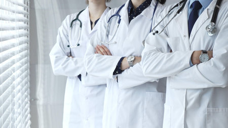 Medical team standing with arms crossed, focusing on healthcare professionals in white lab coats, representing medicine, expertise, and unity in a clinic settingの写真素材