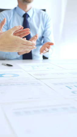 Diverse business people clapping hands in meeting celebrating success with financial charts, performance reports, teamwork, company growth, and management achievementの写真素材