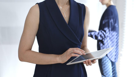 Businesswoman using digital tablet during corporate meeting, collaborating with colleagues in a modern office, planning strategies for project development and successの写真素材