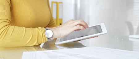 Woman freelancer working with digital tablet, browsing information, using online technology in...