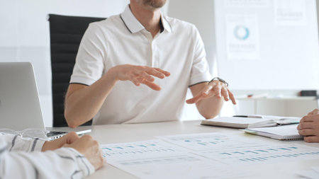 Business team reviewing financial charts, collaborating intently around conference table in...