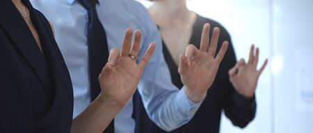 Business professionals showing ok hand gestures during a seminar, symbolizing agreement, teamwork,...