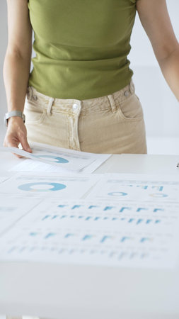 Professional female executive analyzing financial data, pointing toward charts displaying business...