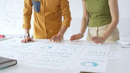 Business team members are reviewing financial data, analyzing charts and graphs, during a productive meeting in a modern office spaceの写真素材