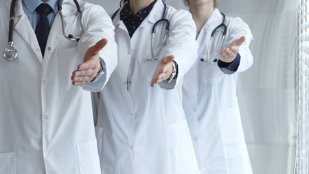 Medical professionals team offering welcoming handshake, ready to greet and assist with healthcare and patient support, establishing trust in hospital environmentの写真素材