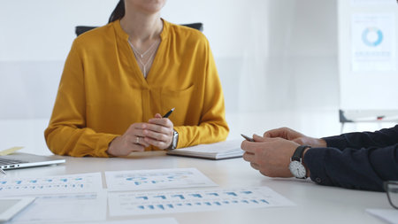 Business professionals gathered around conference table, reviewing financial charts, collaborating on strategic planning and corporate analysisの写真素材