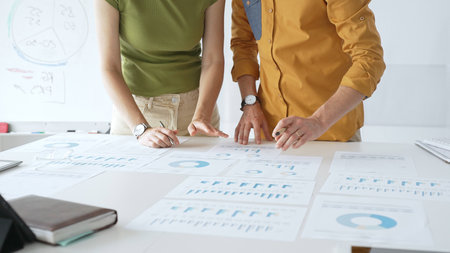 Professional team analyzing financial charts, collaborating intently around conference table in sleek, contemporary workspace. Business people conceptの写真素材
