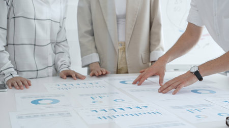 Business team analyzing financial charts and graphs, pointing at statistics and discussing data, working together on business project in modern office. Business people conceptの写真素材