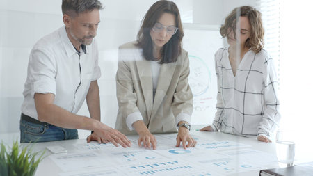 Professional colleagues reviewing financial reports, collaborating on strategic planning in...