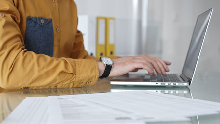 Man working on laptop, typing on keyboard in office, managing business documents and modern technology. Audit and taxes in businessの写真素材