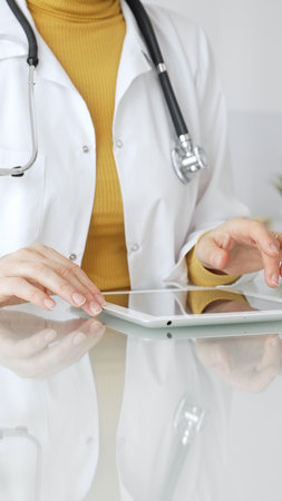 Doctor using tablet, working in clinic office, health care professional analyzing electronic medical records data. Medicine, healthcare and science conceptの写真素材