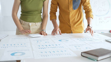 Casual business people are working together, analyzing financial data and reports using a keyboard...