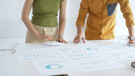 Casual business people are working together, analyzing financial data and reports using a keyboard...