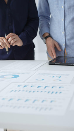 Professional team reviewing financial documents, pointing at charts on desk, collaborating to analyze data and strategize business growth. Business people conceptの写真素材