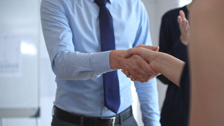 Professional business people shaking hands, concluding a successful partnership agreement and...