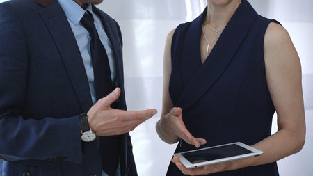 Business colleagues collaborating, discussing strategies, and sharing insights while presenting information on a digital tablet during a professional meetingの写真素材