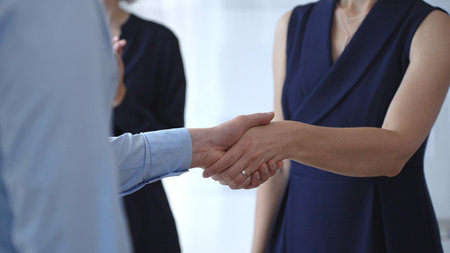 Business woman and businessman in blue shirt shaking hands, concluding a deal, and celebrating...