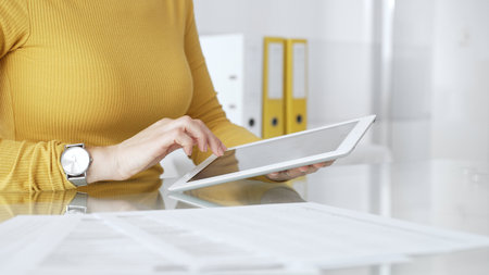 Woman working on digital tablet in office, accessing business documents and technology data. Audit and taxes in businessの写真素材