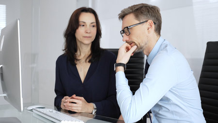 Businesspeople group collaborating and discussing strategies in modern office setting, smiling...