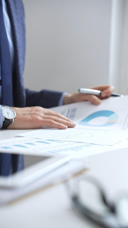 Professional businessman reviewing financial data, analyzing charts and graphs, using laptop, making strategic decisions for business growth. Business people conceptの写真素材