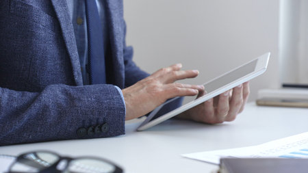 Businessman is using a digital tablet to analyze financial data, working with modern technology in the office to improve productivity and decision making. Business people conceptの写真素材
