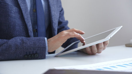 Businessman is using a digital tablet to analyze financial data, working with modern technology in the office for strategic corporate decision making and workflow optimization. Business people conceptの写真素材