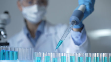 Woman scientist researcher using a micropipette to fill up test tubes with a blue liquid in...