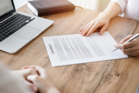 Business people signing contract papers while sitting at the wooden table in office, closeup....