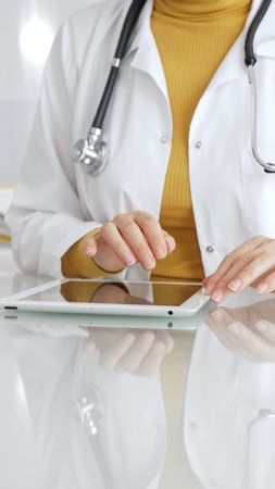 Doctor using tablet, working in clinic office, health care professional analyzing electronic medical records data. Medicine, healthcare and science conceptの写真素材