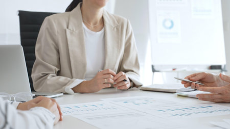 Business team analyzing financial data and discussing marketing strategy during a meeting in the office, businesswoman pointing at charts and explaining strategy to colleaguesの写真素材