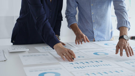 Professional team reviewing financial documents, pointing at charts on desk, collaborating to analyze data and strategize business growth. Business people conceptの写真素材