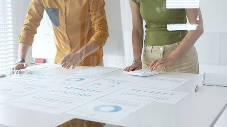 Casual business people are working together, analyzing financial data and reports using a keyboard...