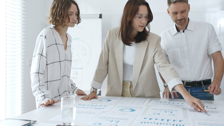Professional team reviewing financial data, collaborating on working documents, demonstrating team...