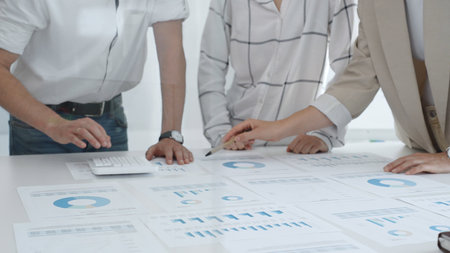 Professional team reviewing financial charts and graphs, working together in modern office space,...