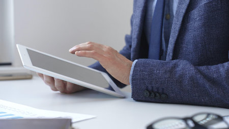 Businessman is using a digital tablet to analyze financial data, working with modern technology in the office for strategic corporate decision making and workflow optimization. Business people conceptの写真素材