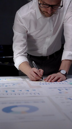 Professional businessman working late nights in office, analyzing financial data and statistics,...
