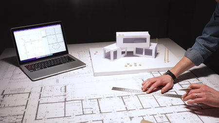 Architect carefully drafting detailed building blueprint plans, developing structural engineering...